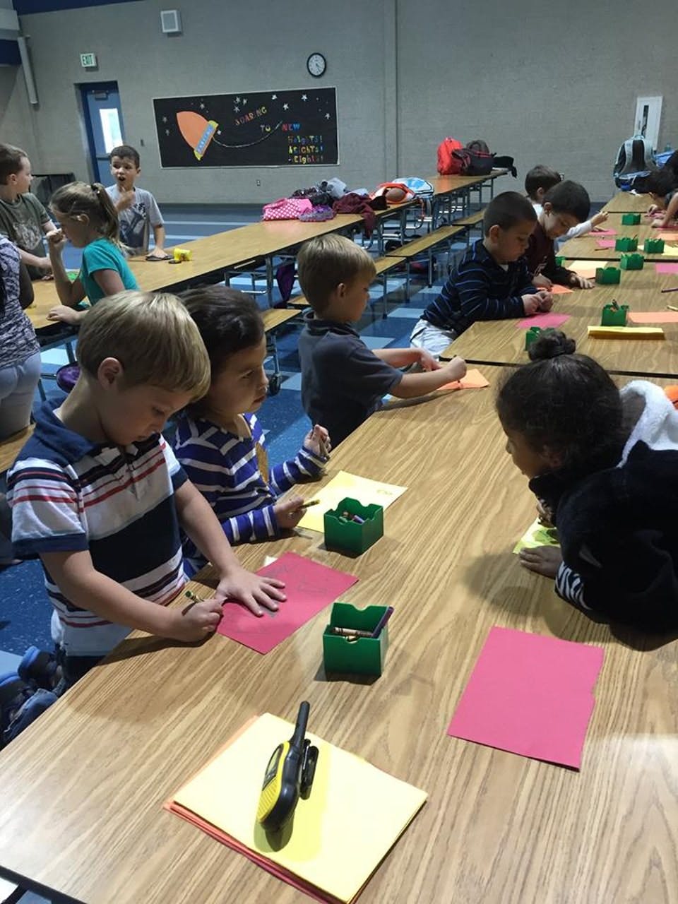 Children sitting at tables doing crafts with paper and crayons