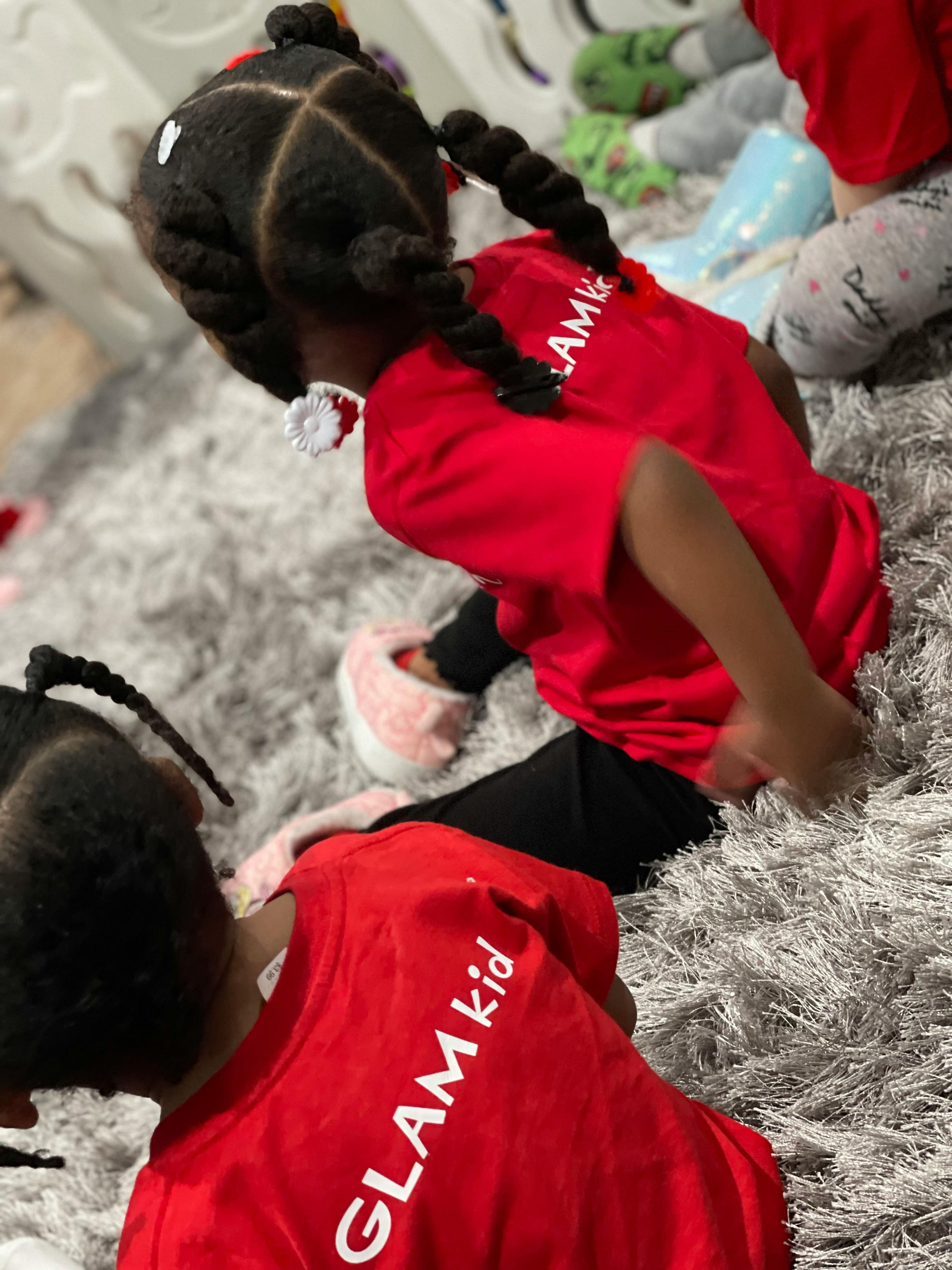 Two children in red shirts on a gray rug