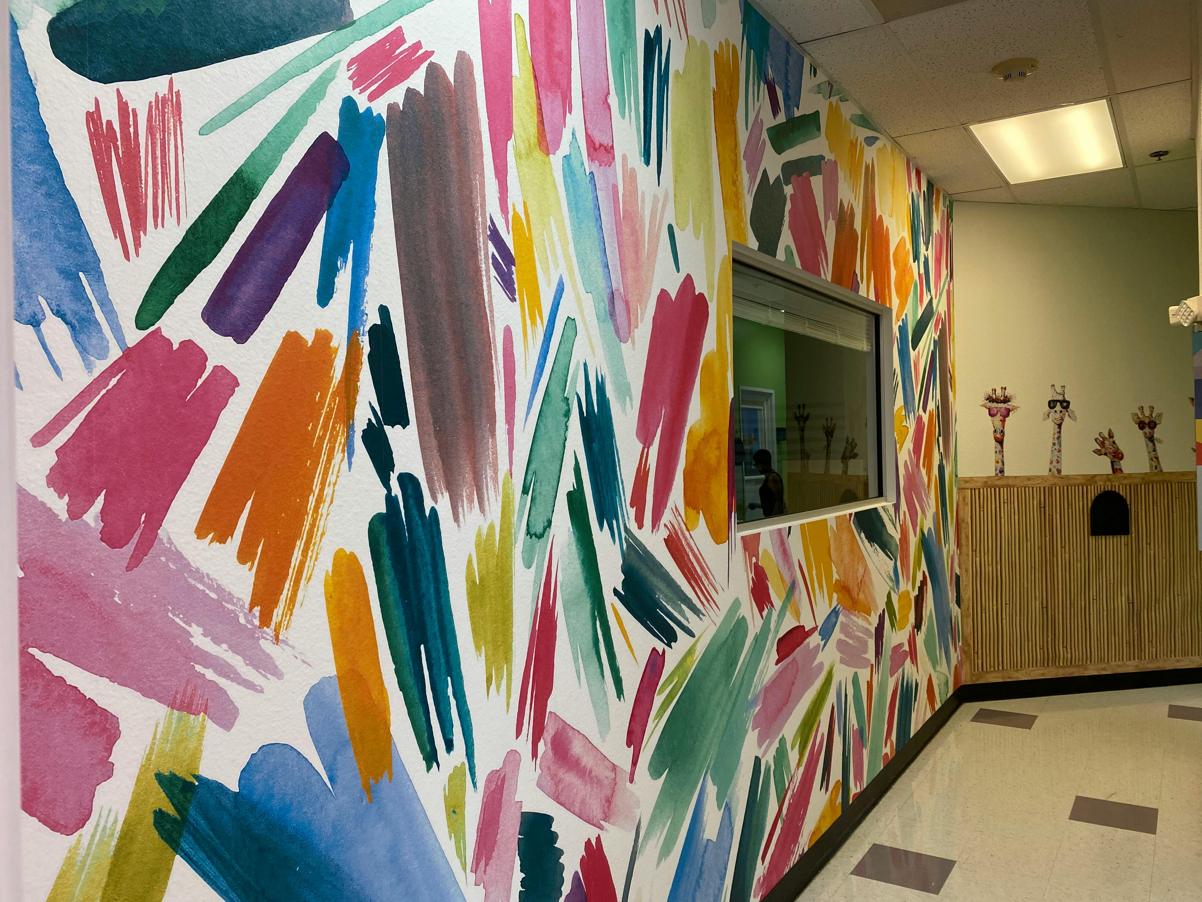 Wall with colorful brushstroke pattern and a window looking into a room