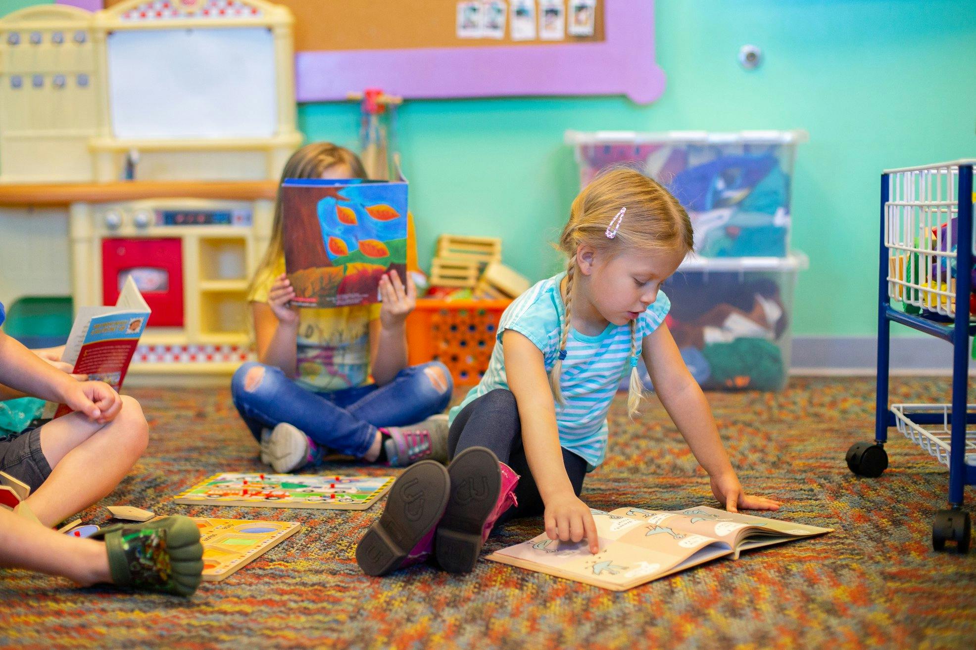 Three children sitting on the floor reading books