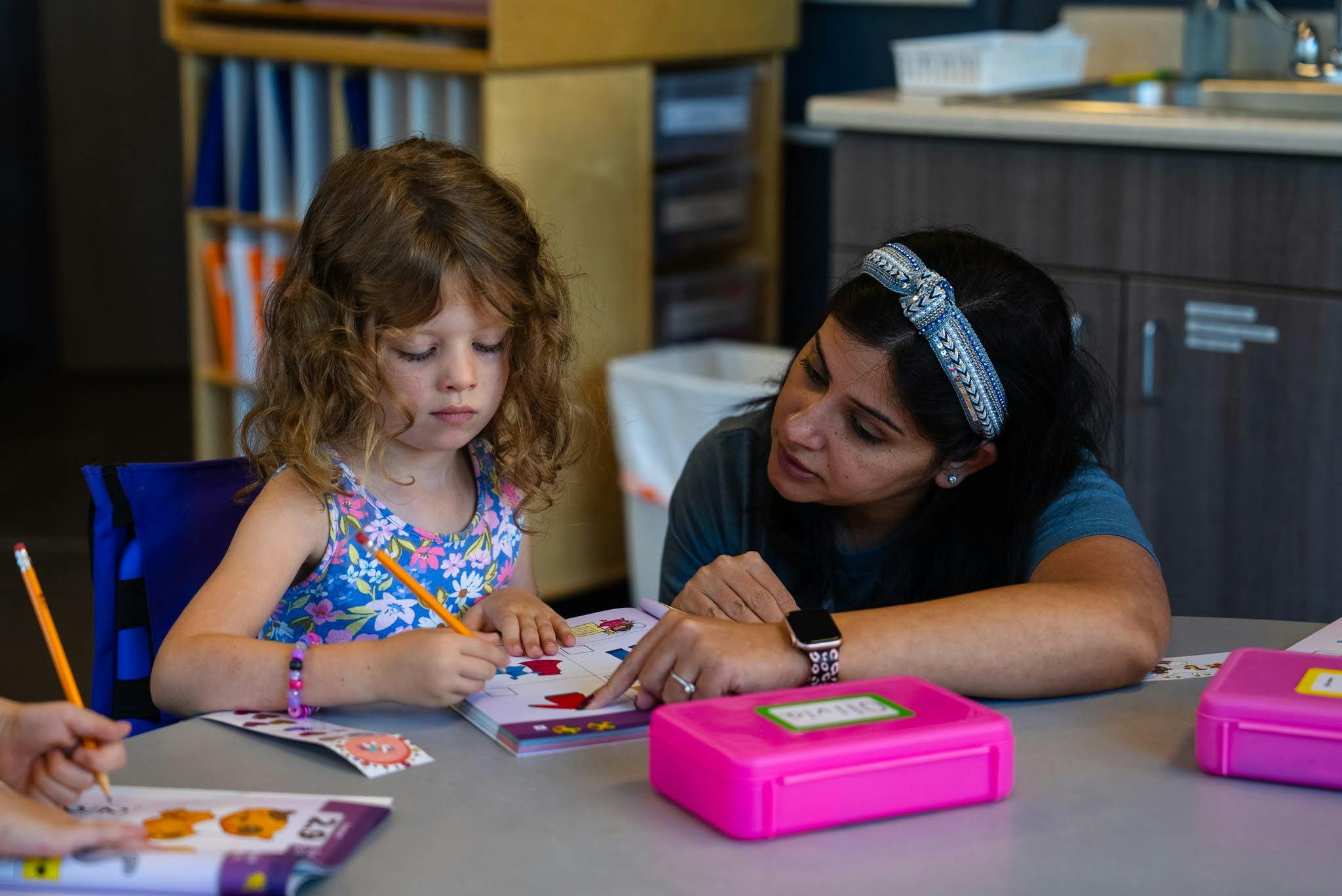 Adult and child looking at a book together in a classroom