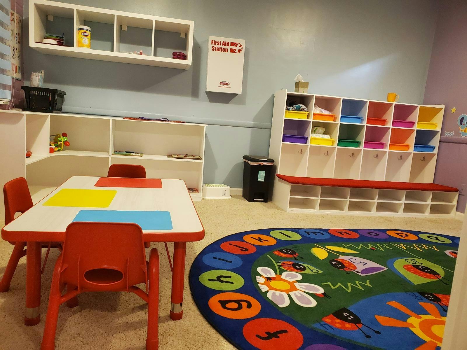 Children's classroom with small table and chairs, storage cubbies, and colorful rug