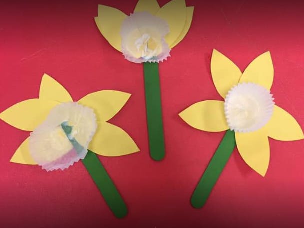 Three paper flowers with yellow petals and green stems