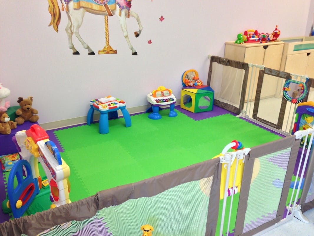 Play area with green floor mats and various colorful toys
