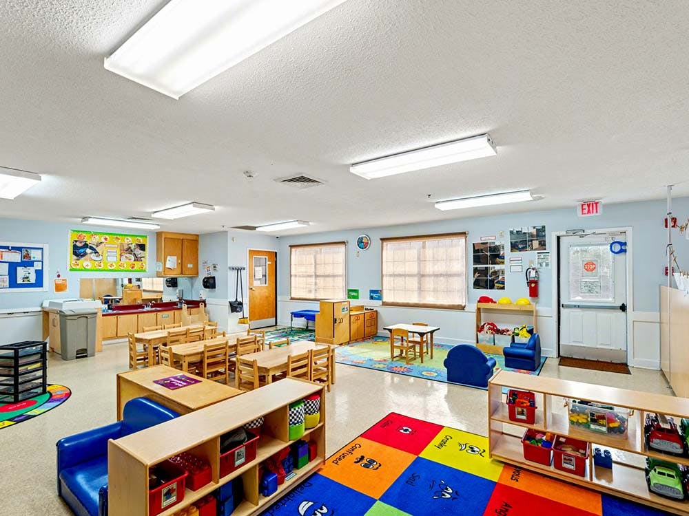 Classroom with small tables, chairs, and play areas