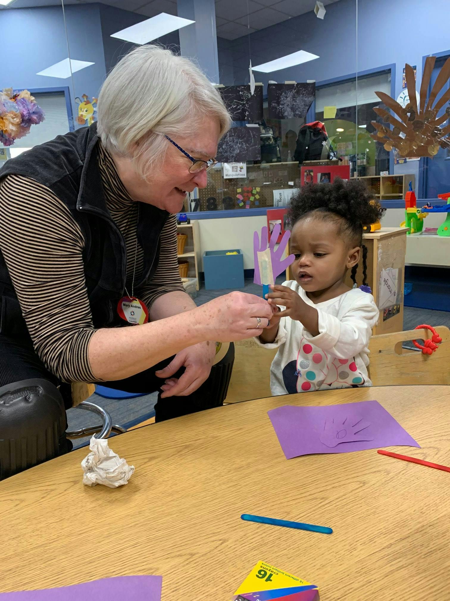 Adult and child interacting at a table in a classroom