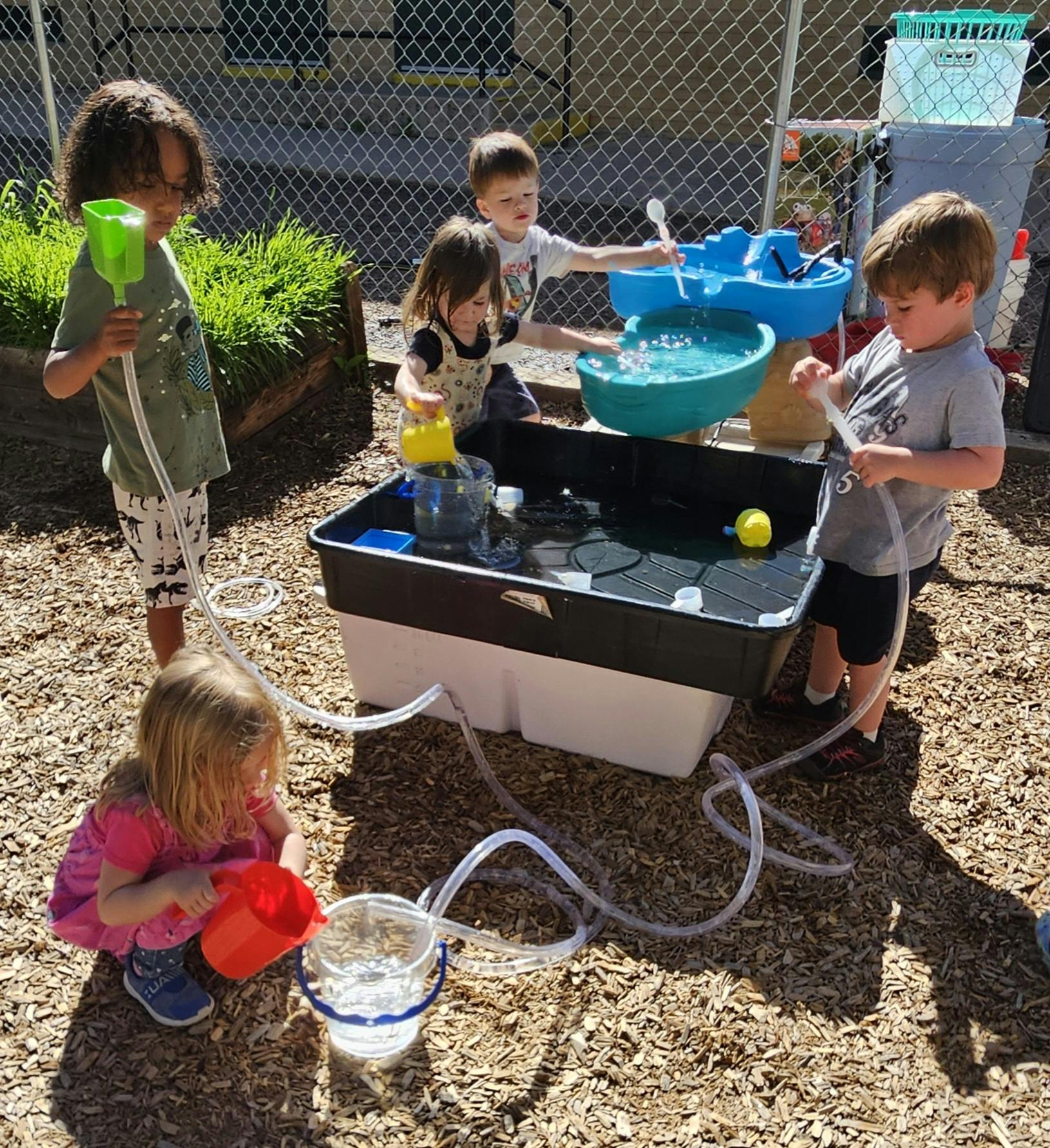 Children playing with a water table and tubes outdoors