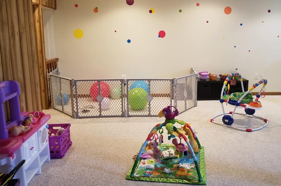 Playroom with baby gate, play mat, and various toys