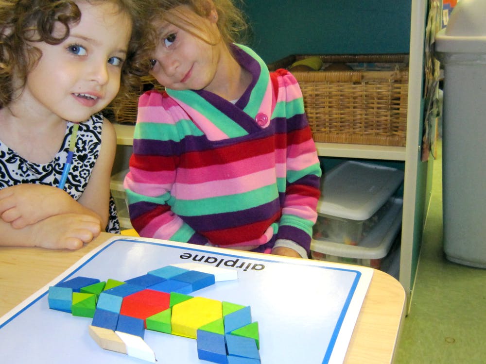 Two children looking at the camera, with a block airplane on a table