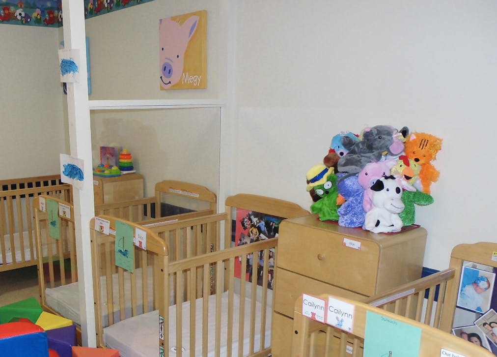 Multiple cribs in a room with stuffed animals on a dresser