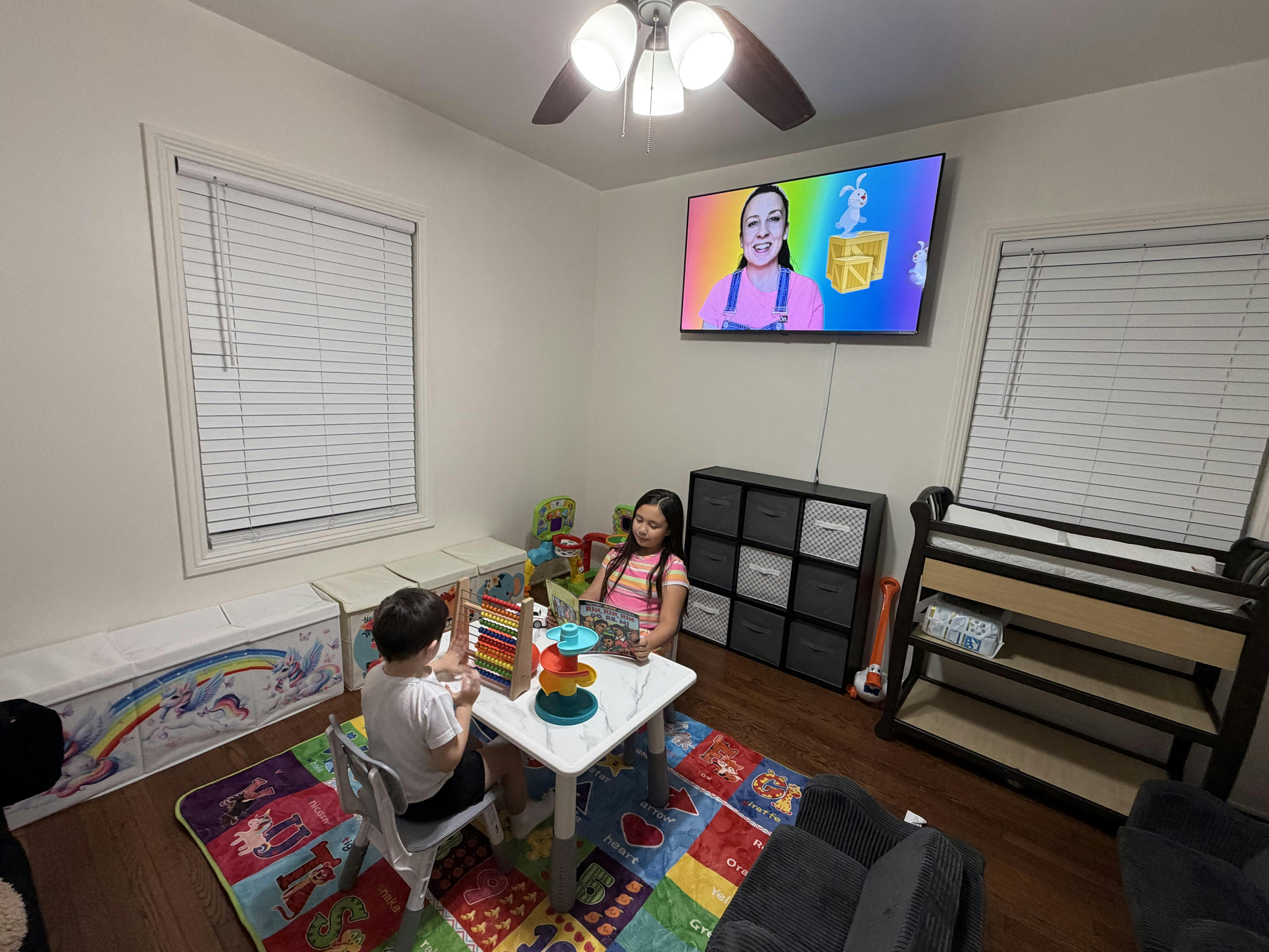 Two children sitting at a table with an abacus and book in a playroom