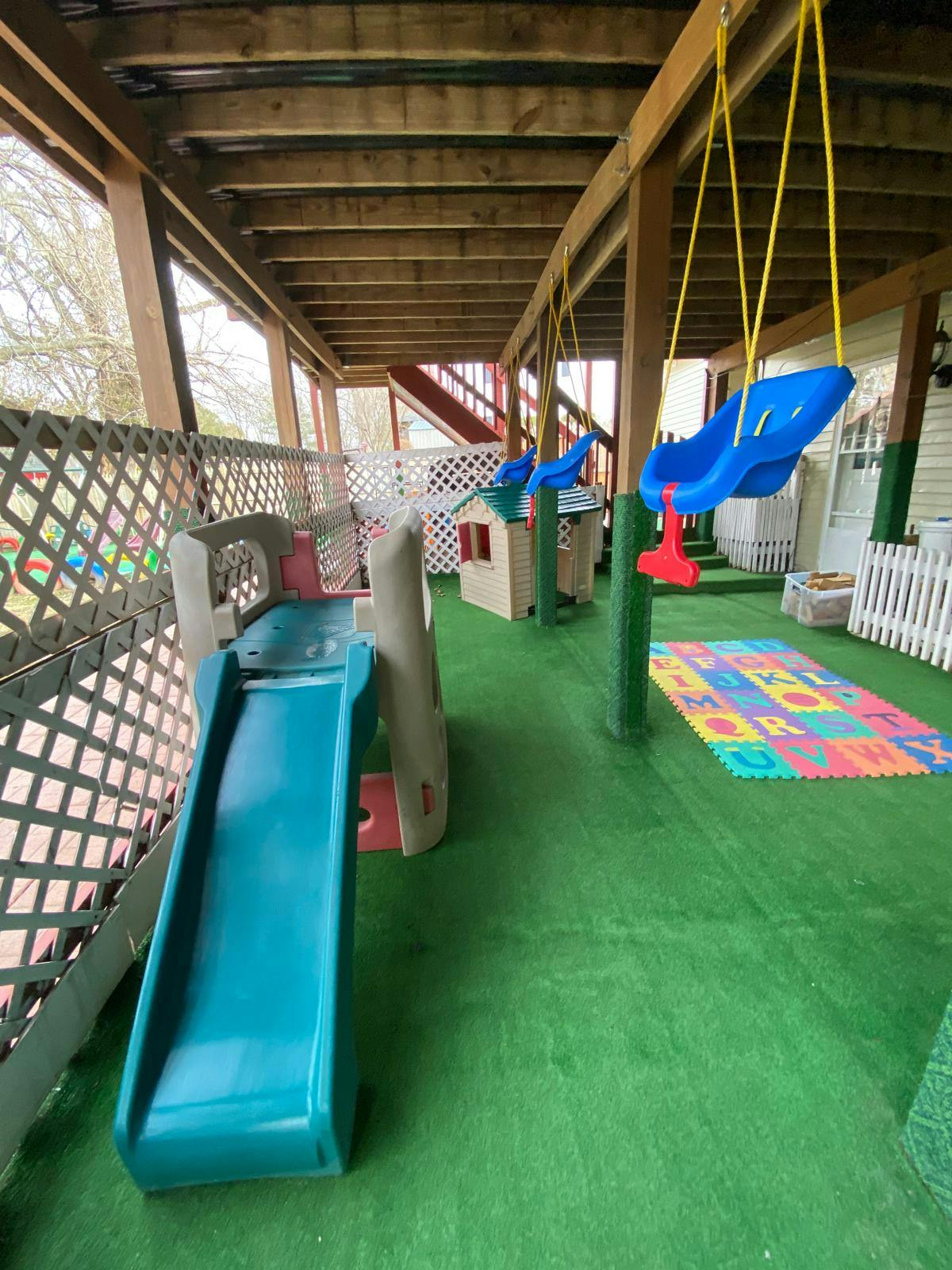 Playground area with swings, slide, and a letter mat