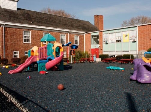 Playground with colorful play structure and red brick building in background