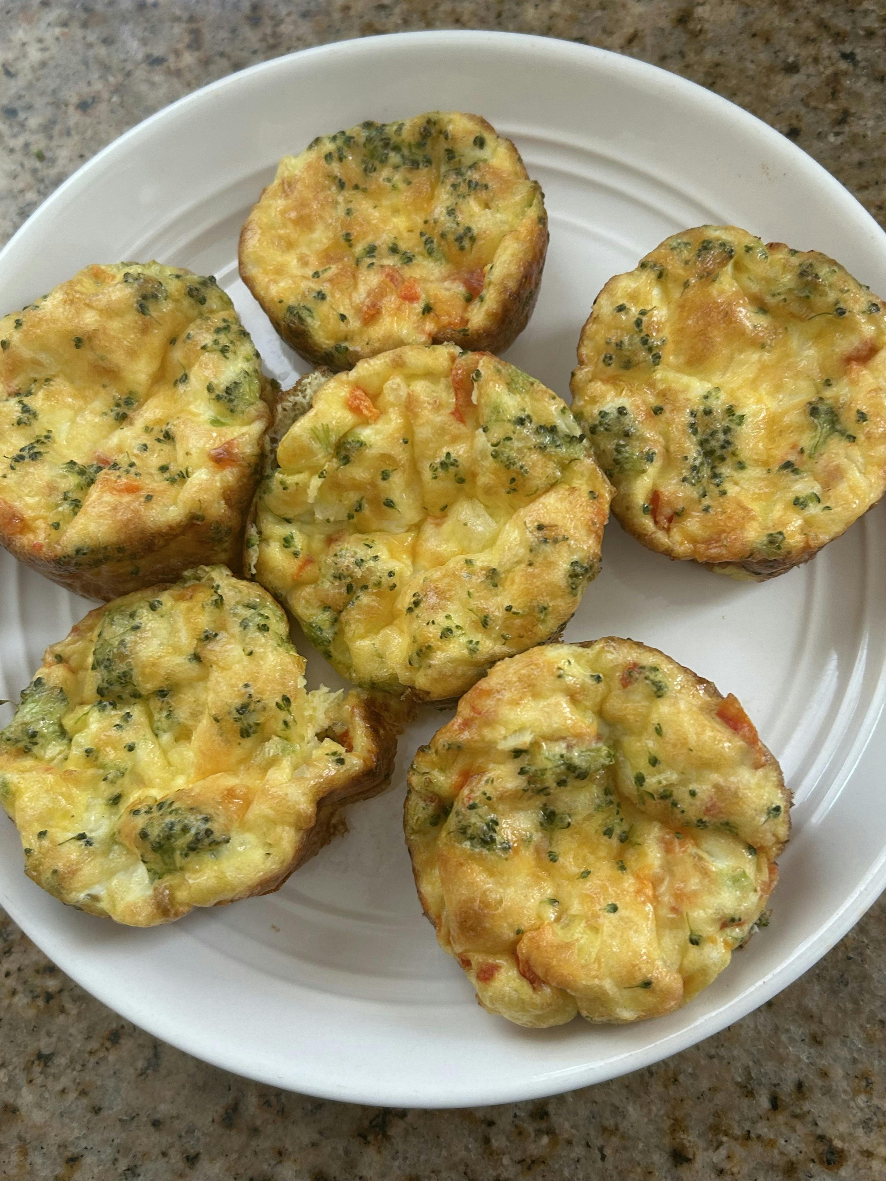 Several baked egg bites with broccoli on a white plate