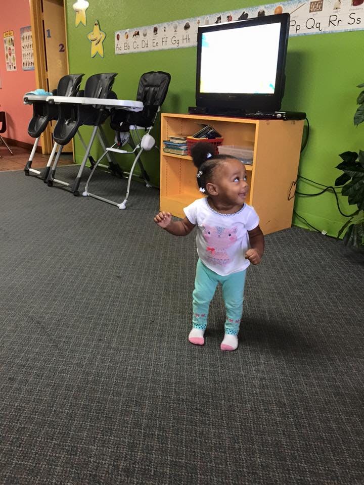 Child standing in a room with high chairs and a television
