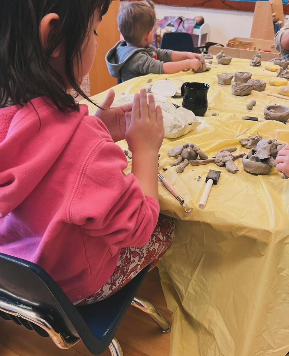 Children working with clay at a table in a classroom