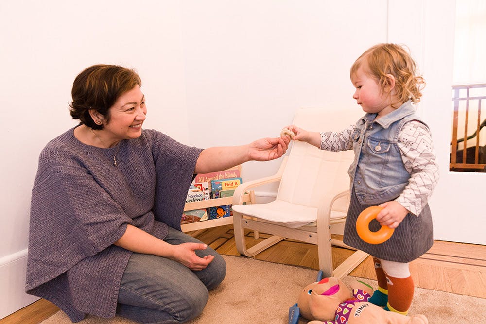 Adult and child interacting, adult handing object to child