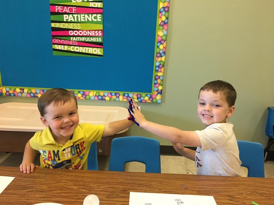Two children high-fiving in a classroom