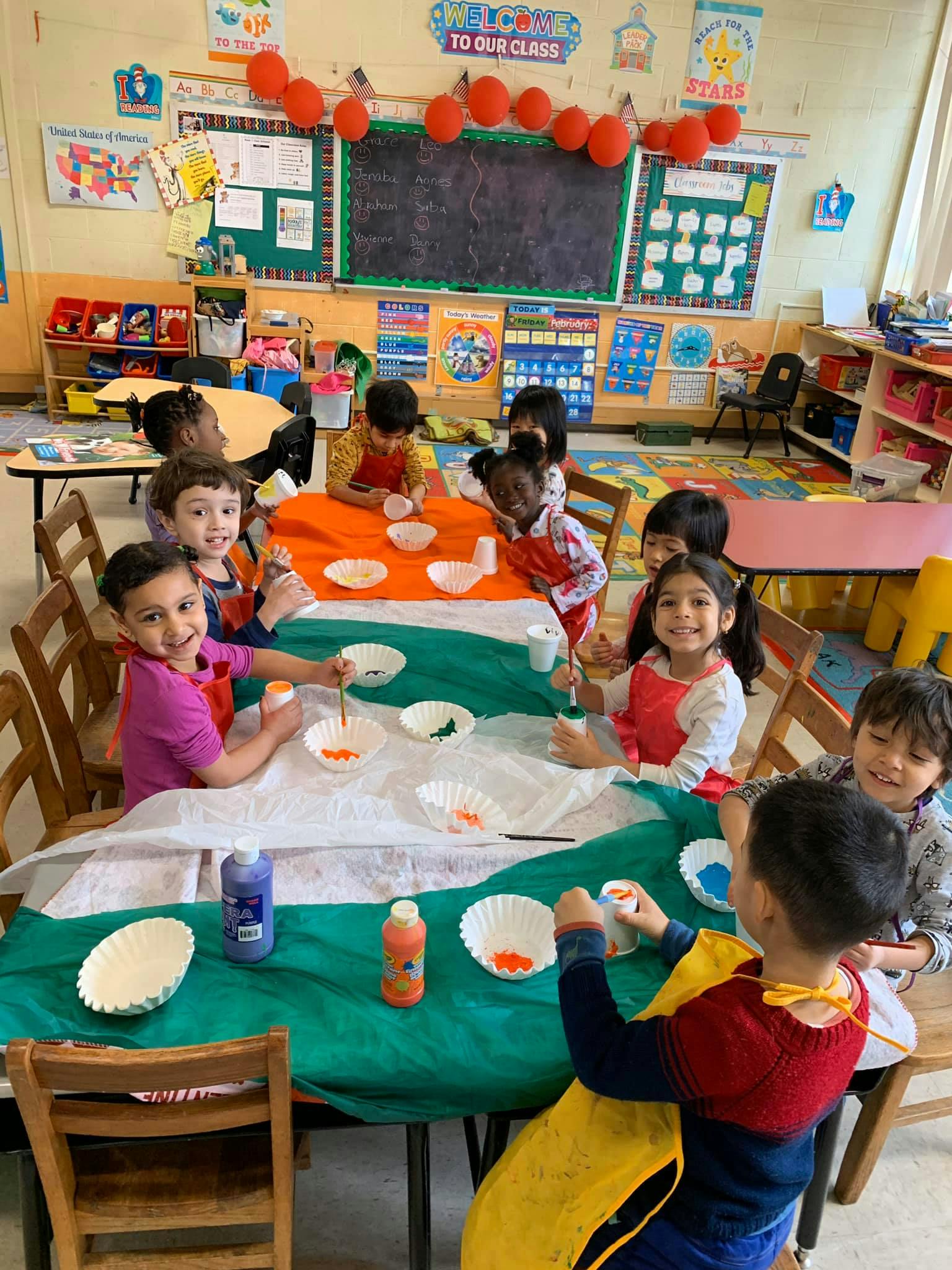 Children painting at a table in a classroom
