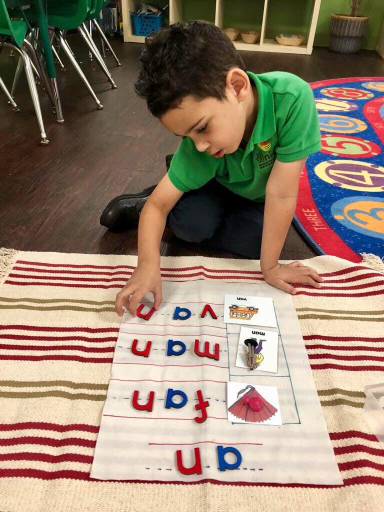 Child on floor arranging letter tiles on a mat