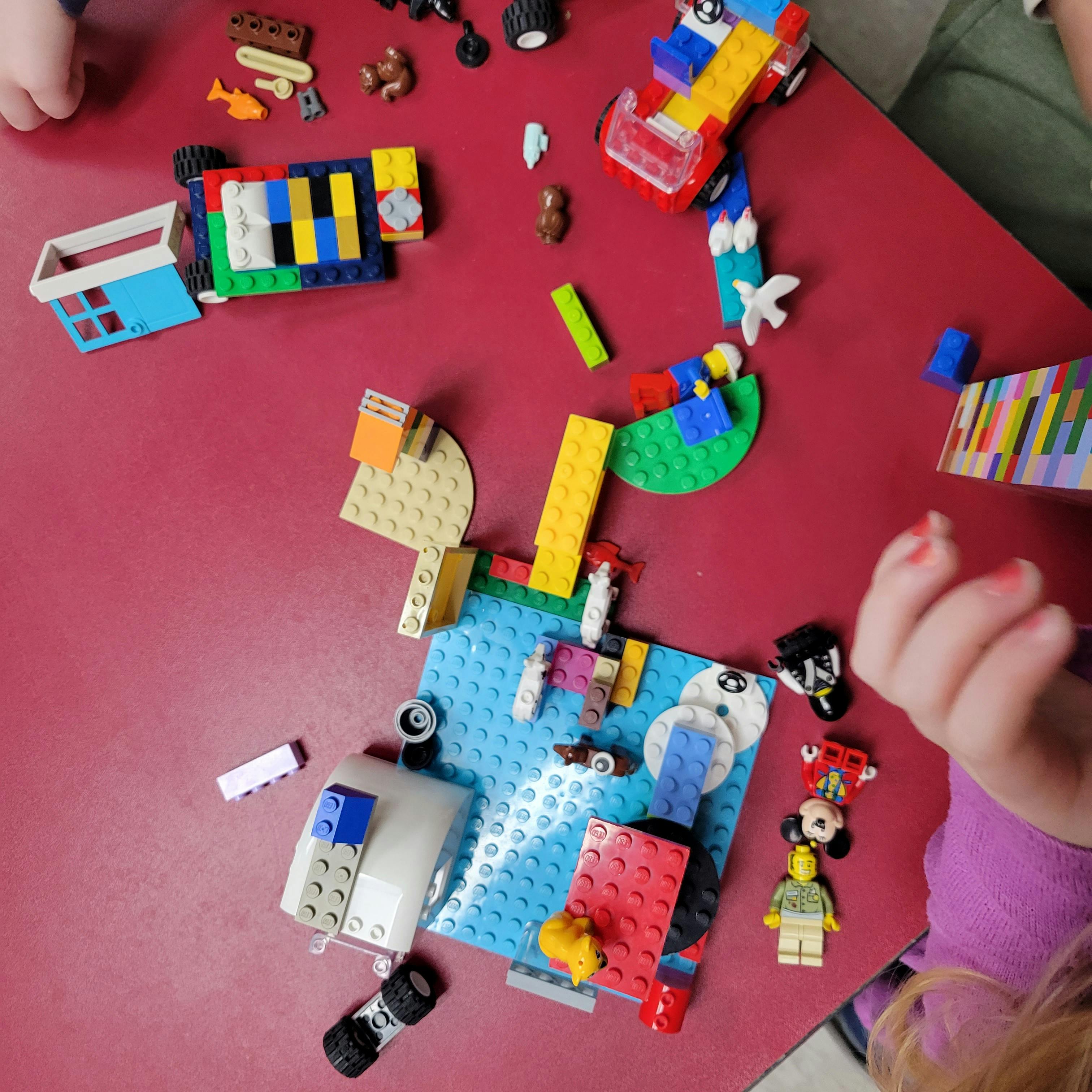 Children playing with colorful building blocks on a red table
