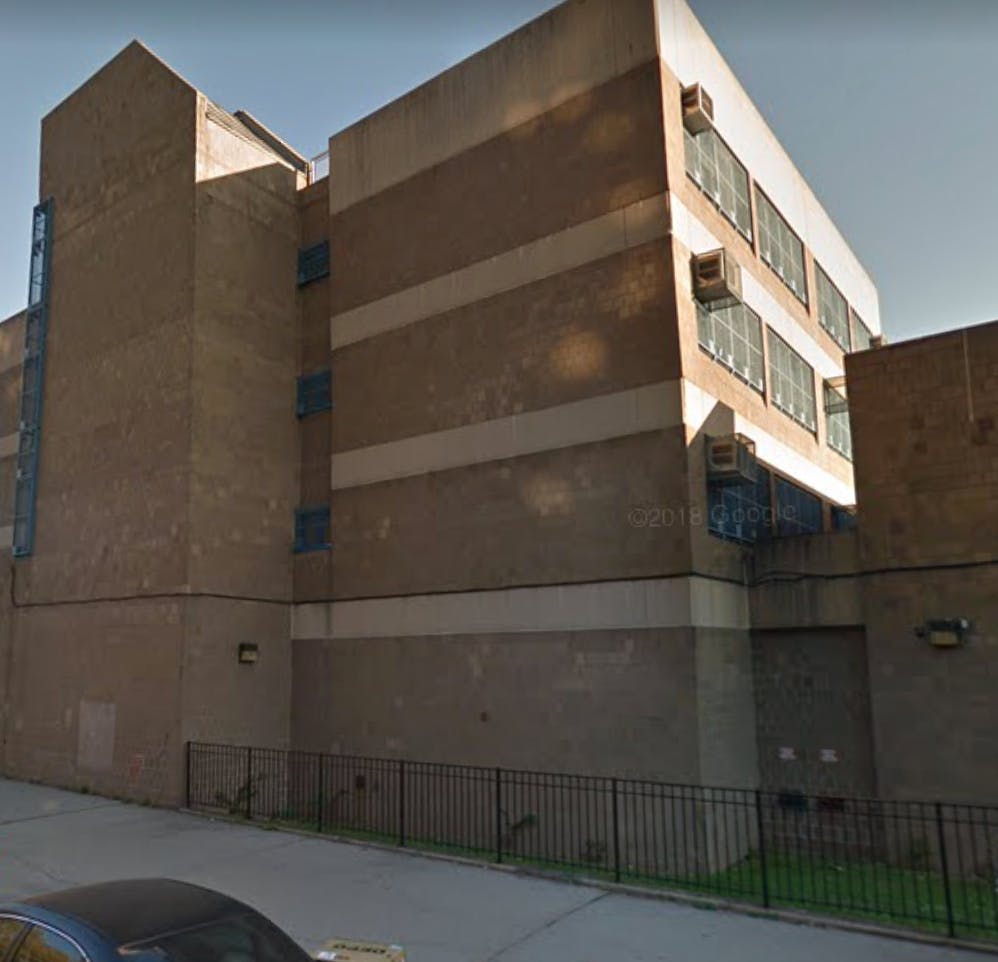Large brick building with multiple windows and a fence in front of it