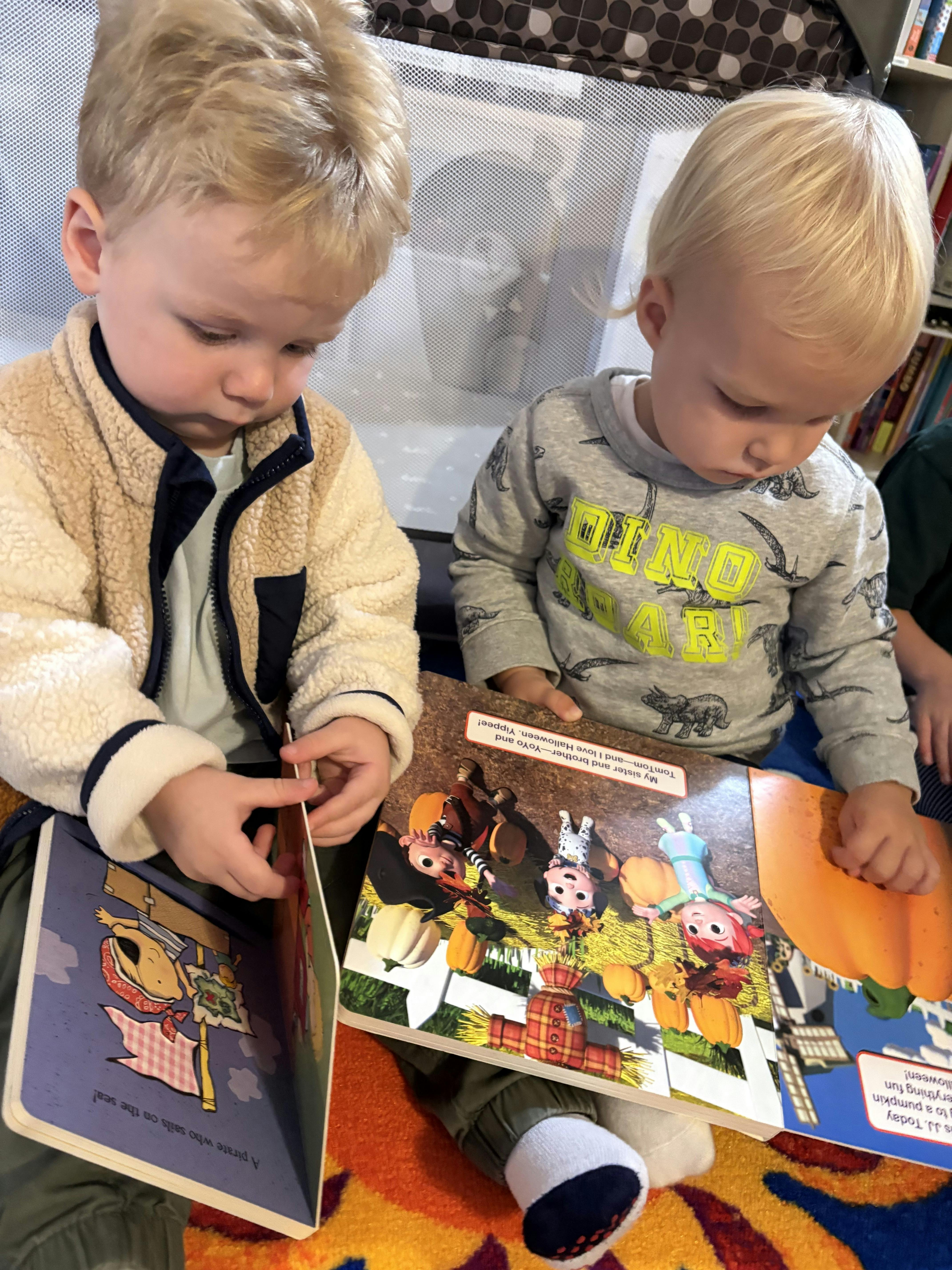 Two children sitting on the floor looking at books