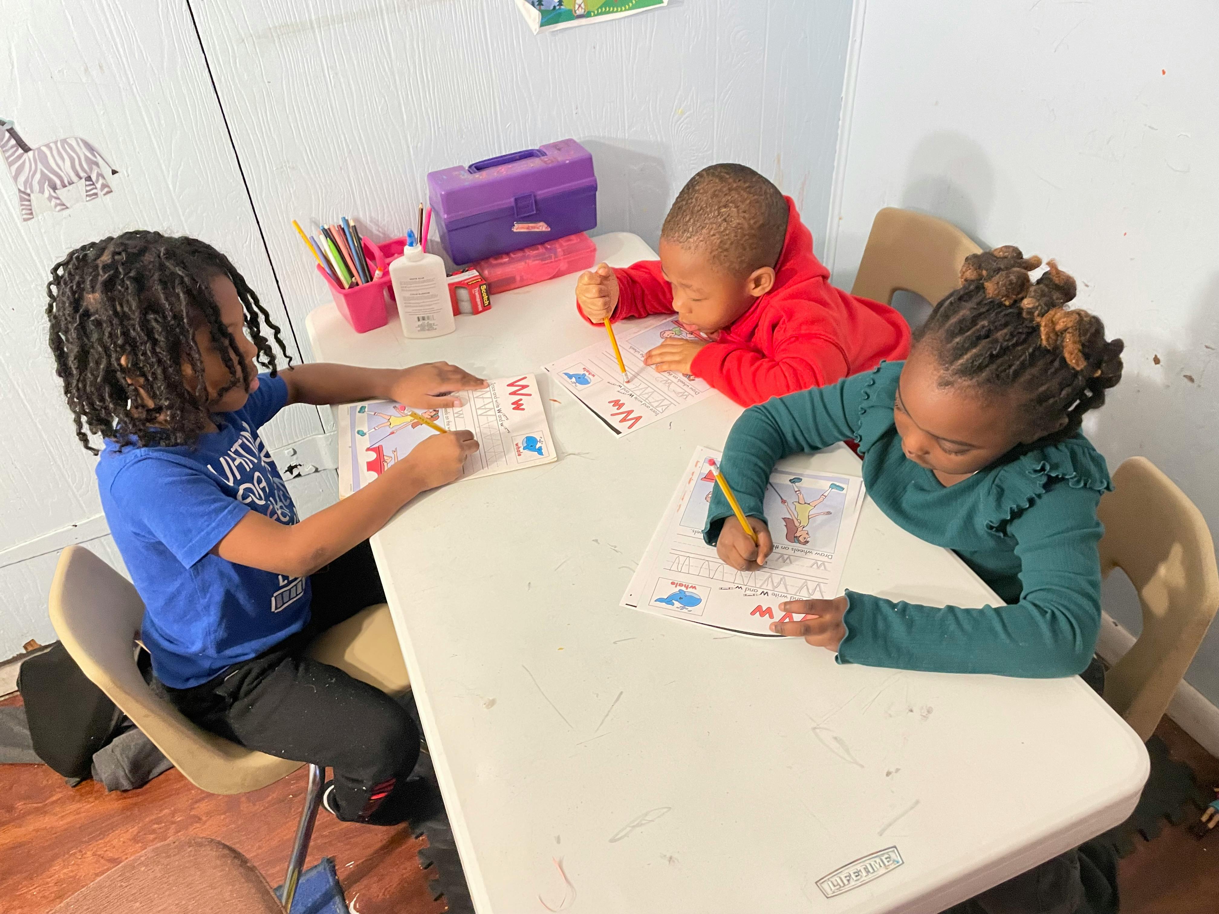 Three children drawing at a table