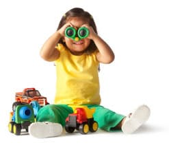 Child sitting on floor looking through toy binoculars with toy trucks