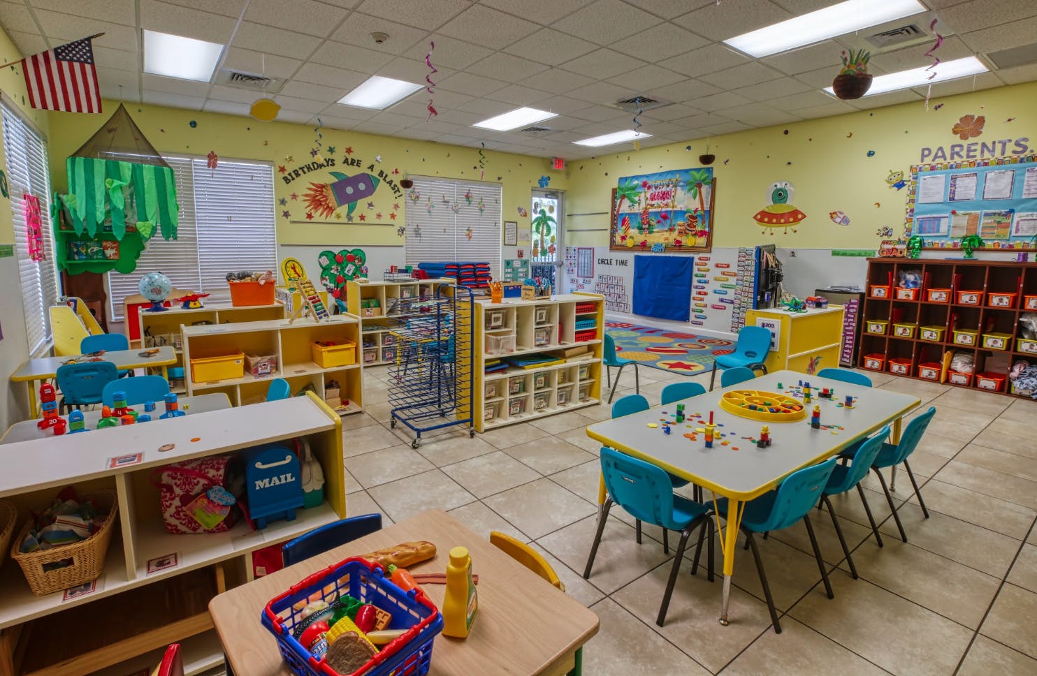 Colorful classroom with small tables and chairs, shelves, and decorations