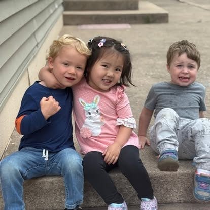 Three children sitting together on outdoor concrete steps