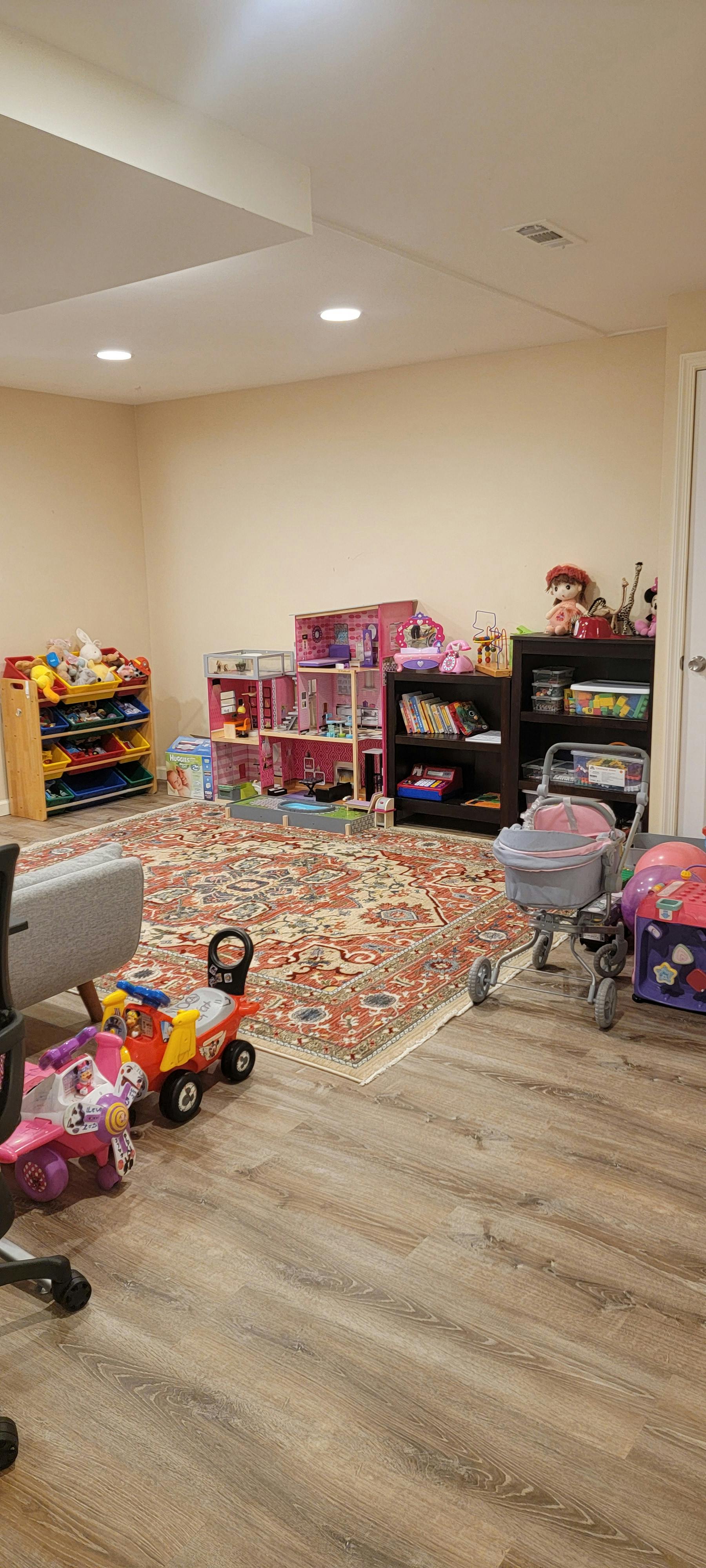 Playroom with a dollhouse, toy stroller, and shelves filled with children toys