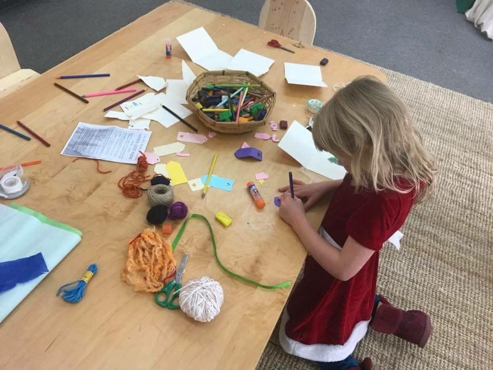 Child drawing at a table with craft supplies