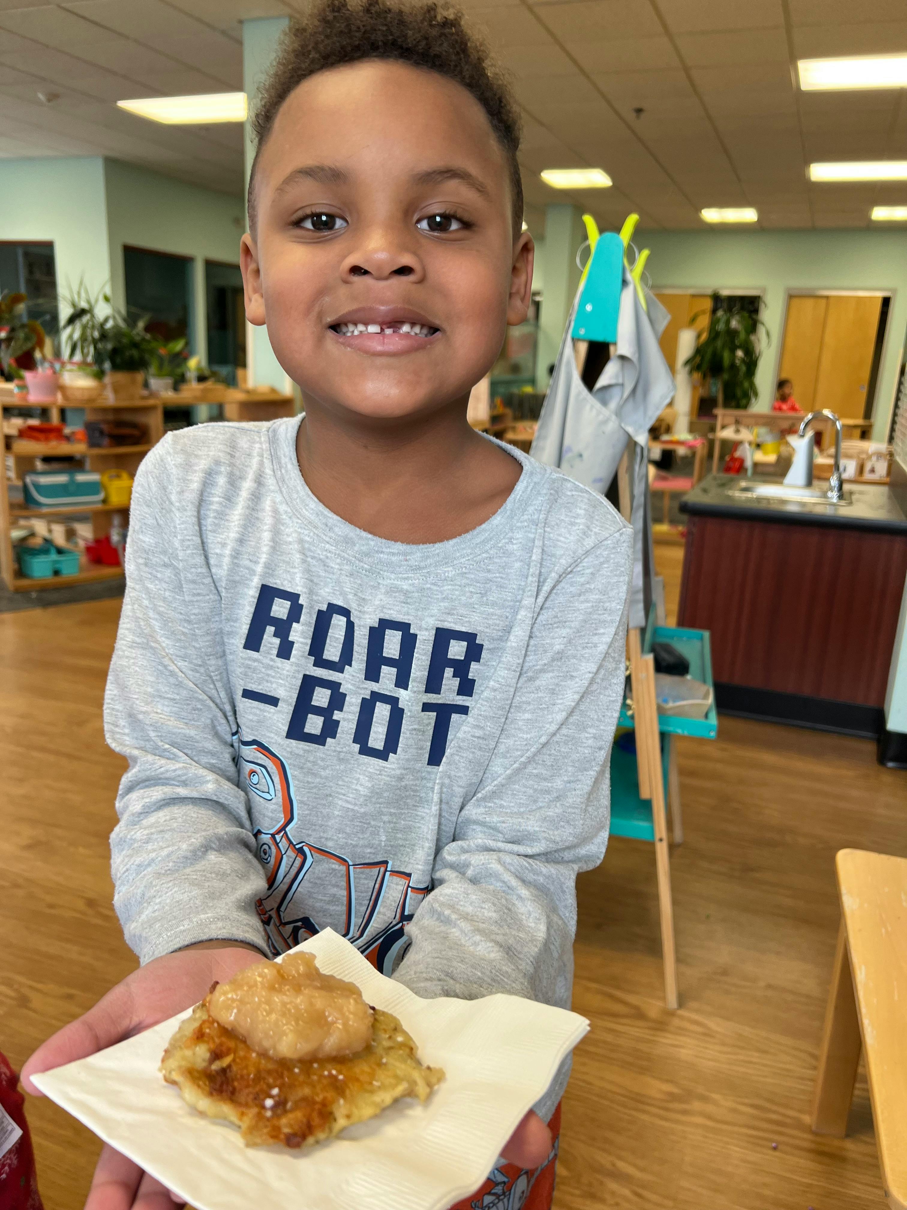 Child holding a small pancake with topping