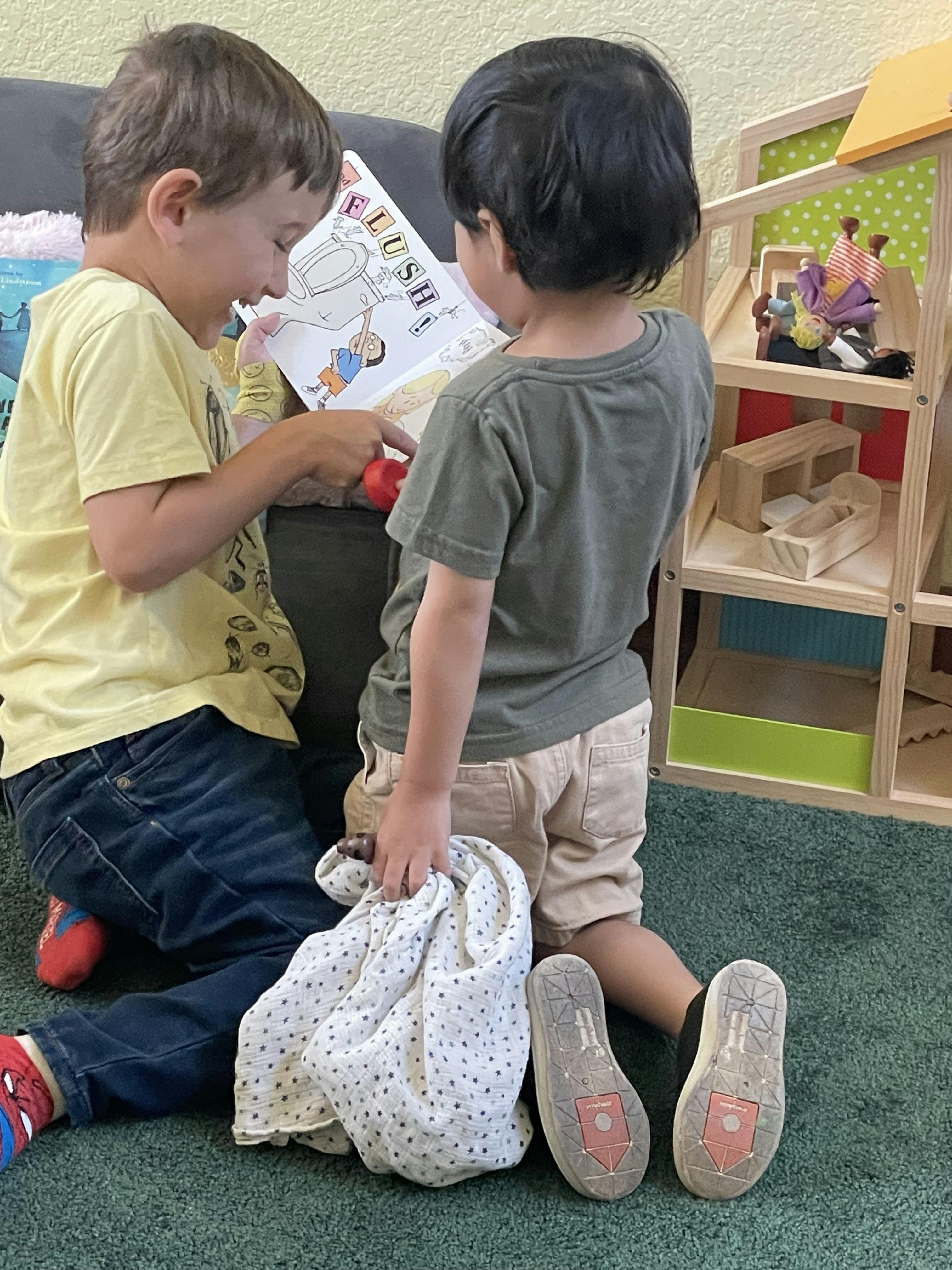 Two children reading a book together that shows a toilet with the word "FLUSH"