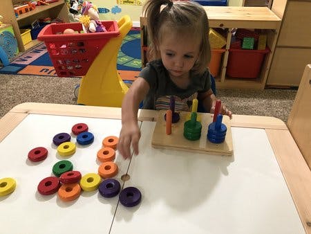 Child playing with colorful stacking rings on a table