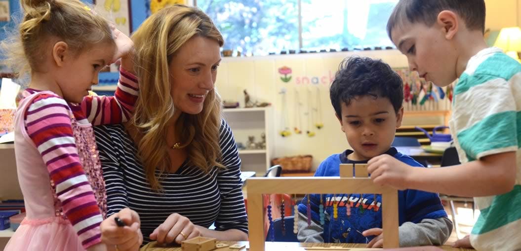 Adult and three children interacting with a wooden toy
