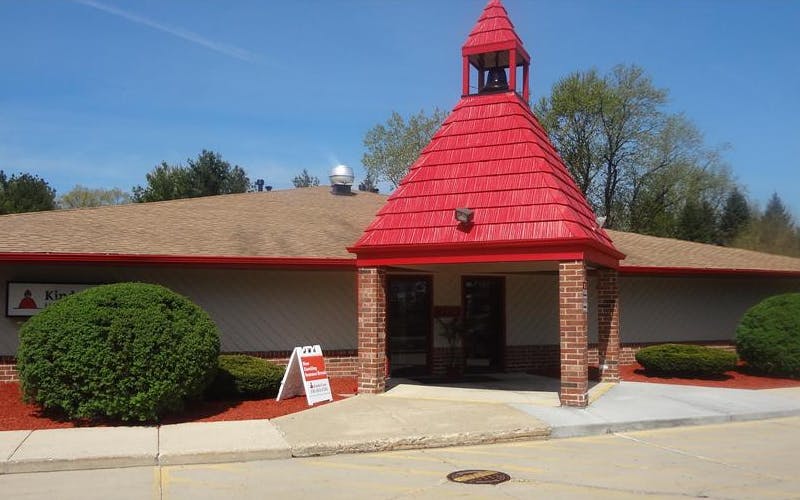 Entrance to a building with a red pointed roof and a bell tower