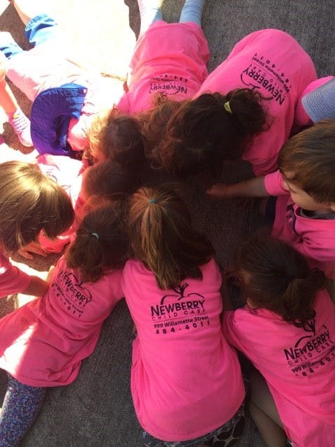 Group of children in pink shirts with "NEWBERRY CHILD CARE" text