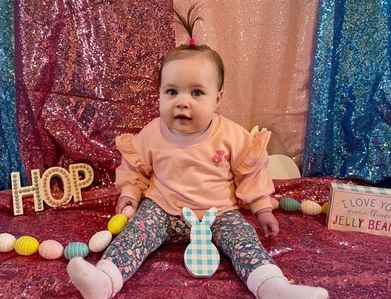 Child sitting on a sparkly surface with a bunny cutout and decorative eggs