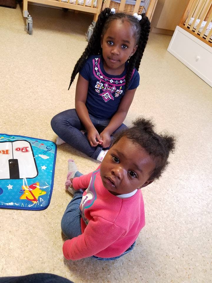 Two children sitting on the floor, one in front of the other