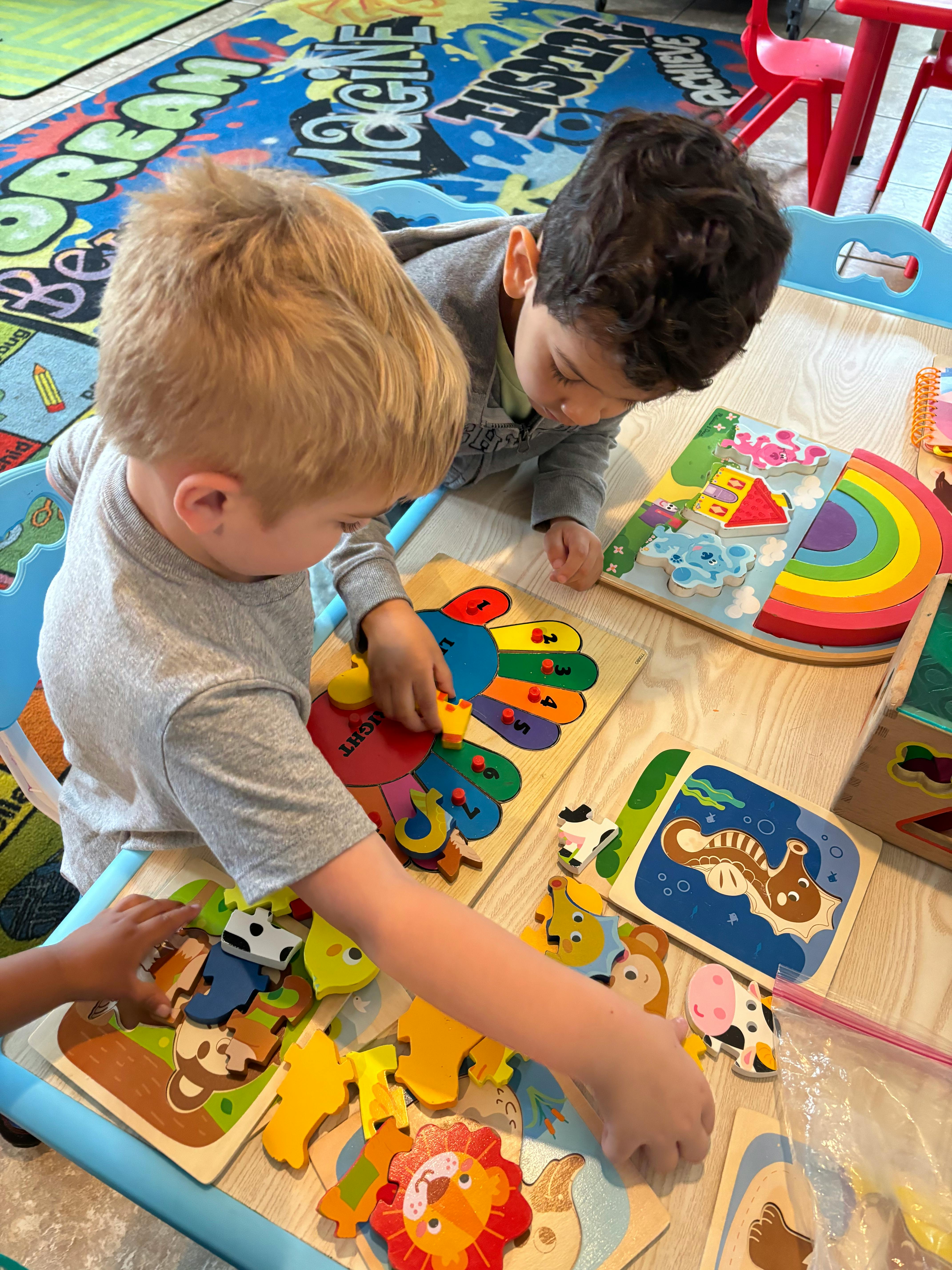 Two children playing with puzzles on a table