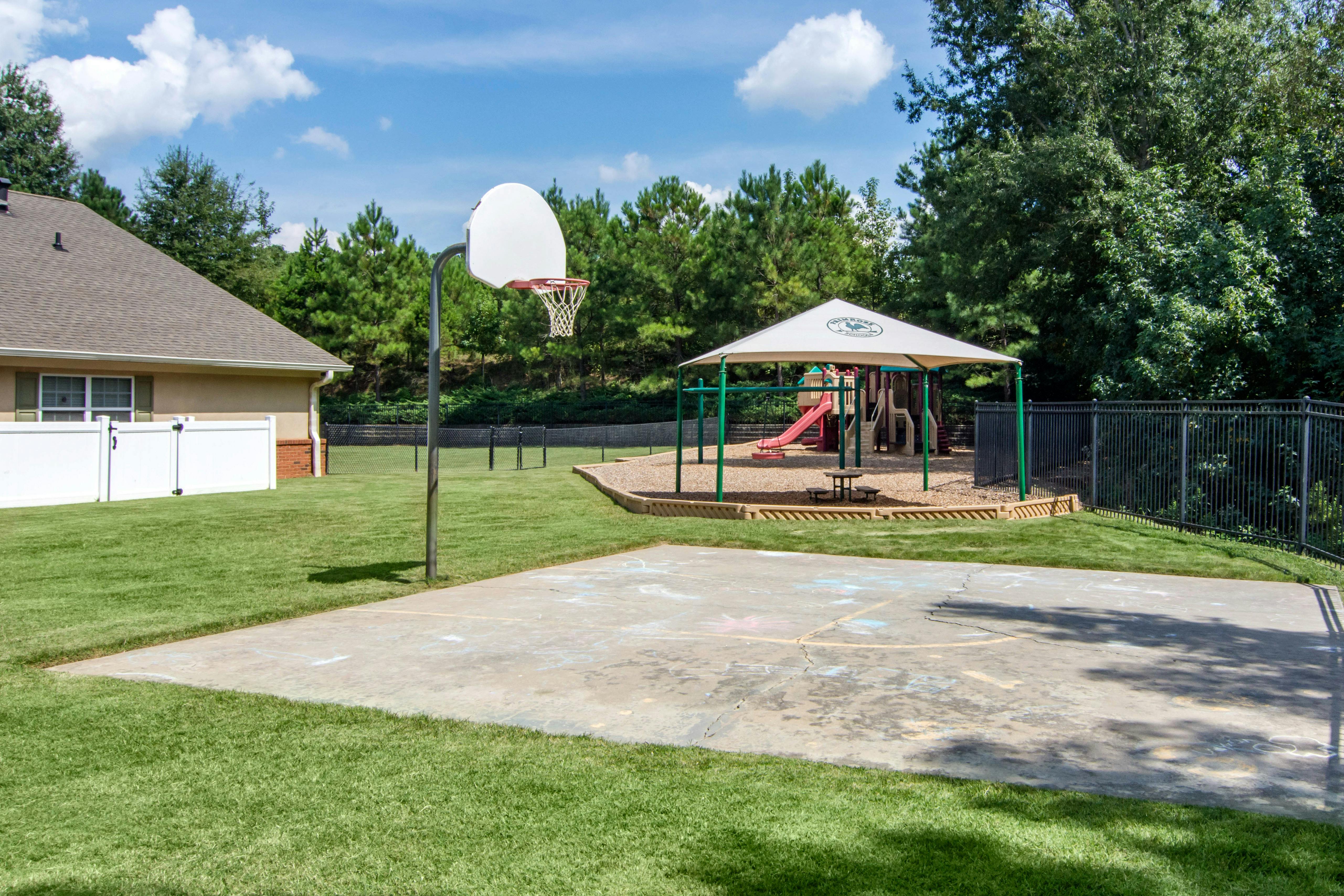 Basketball hoop next to a children's playground with a white sunshade