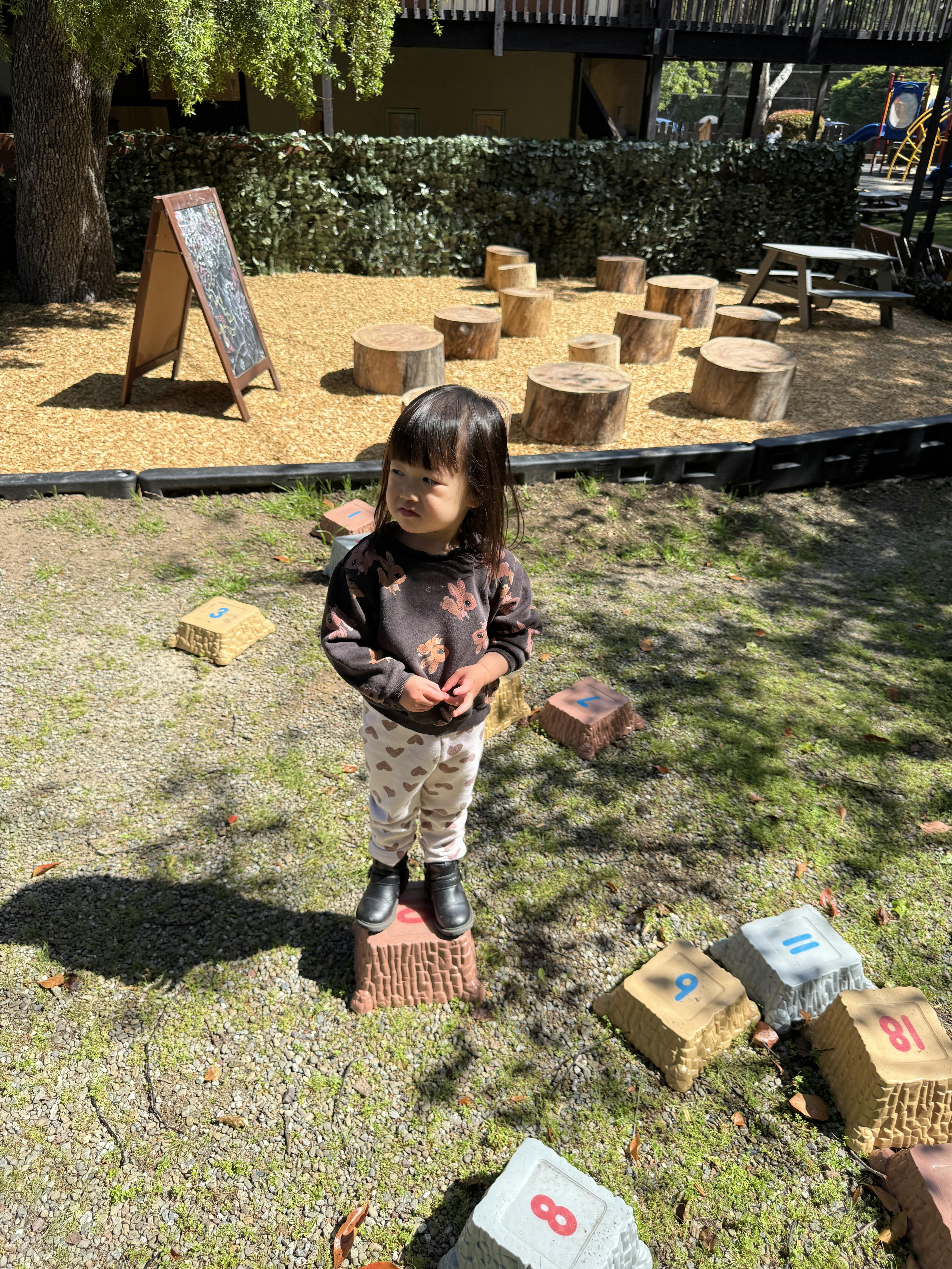 Child standing on a numbered step in a play area