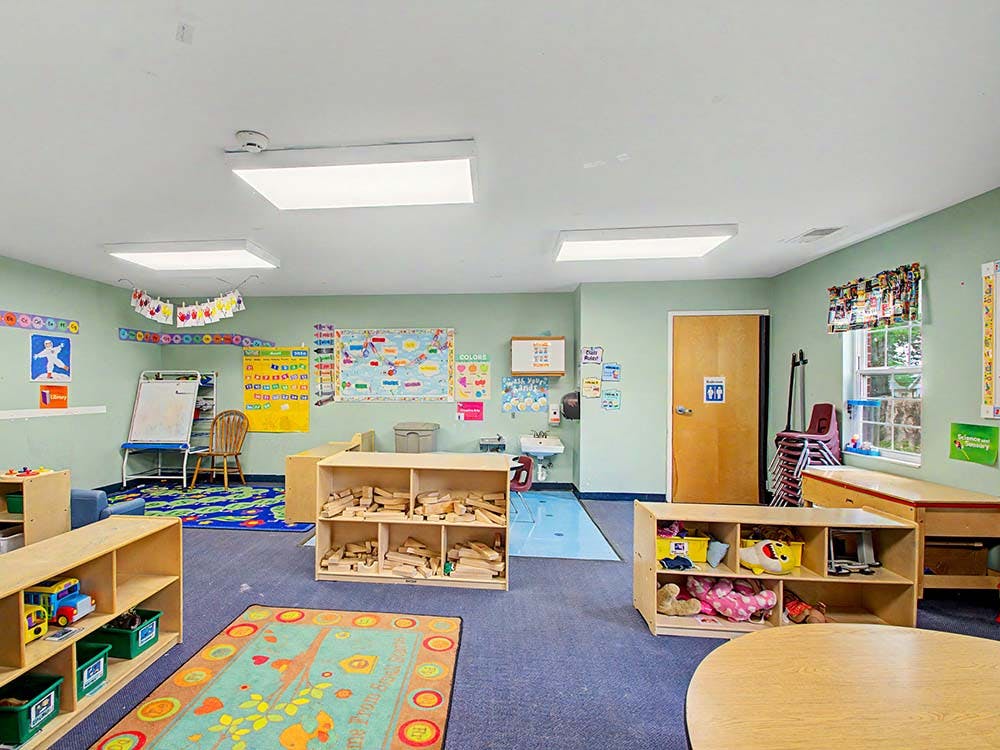 Empty classroom with light green walls, educational posters, and toy shelves