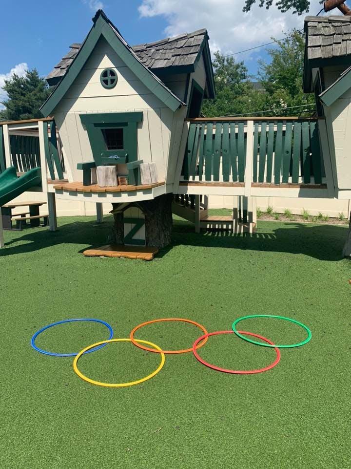 Playhouse with green trim and multiple colorful hoops on artificial grass