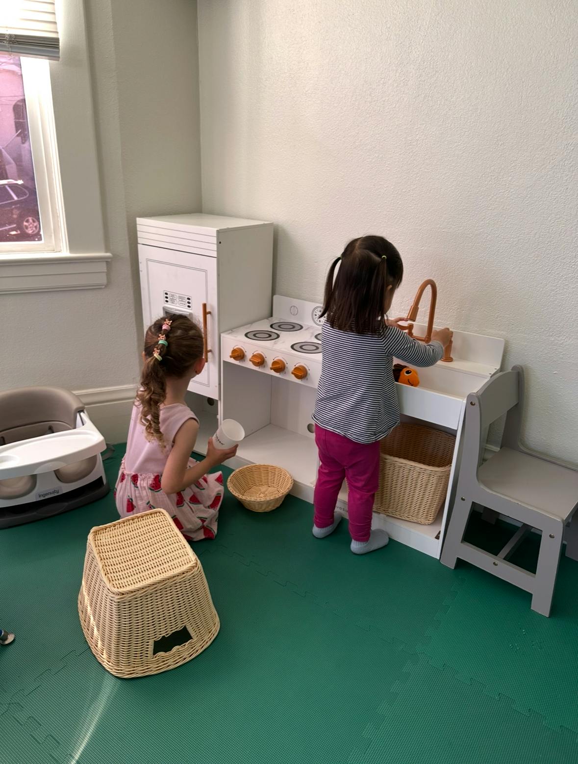 Two children playing with a toy kitchen set