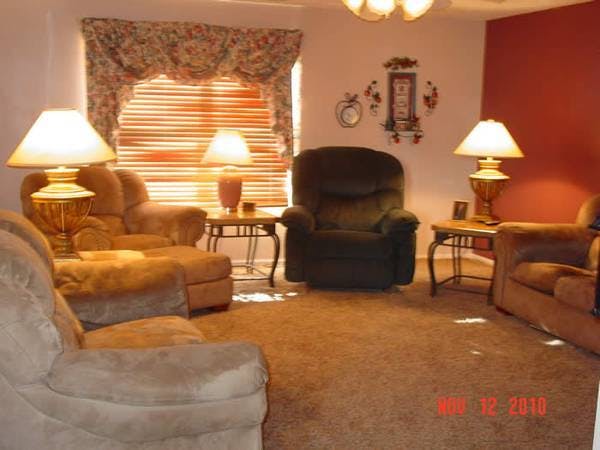 Living room with multiple armchairs, lamps, and a window with blinds