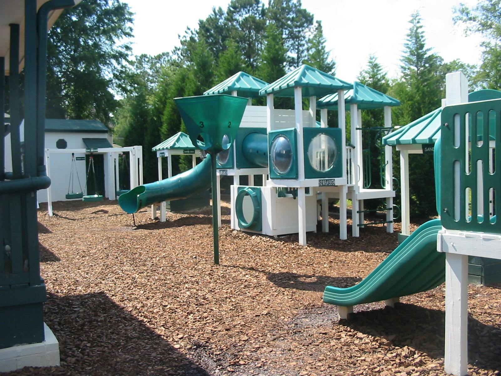 Playground with green and white play structure and slides