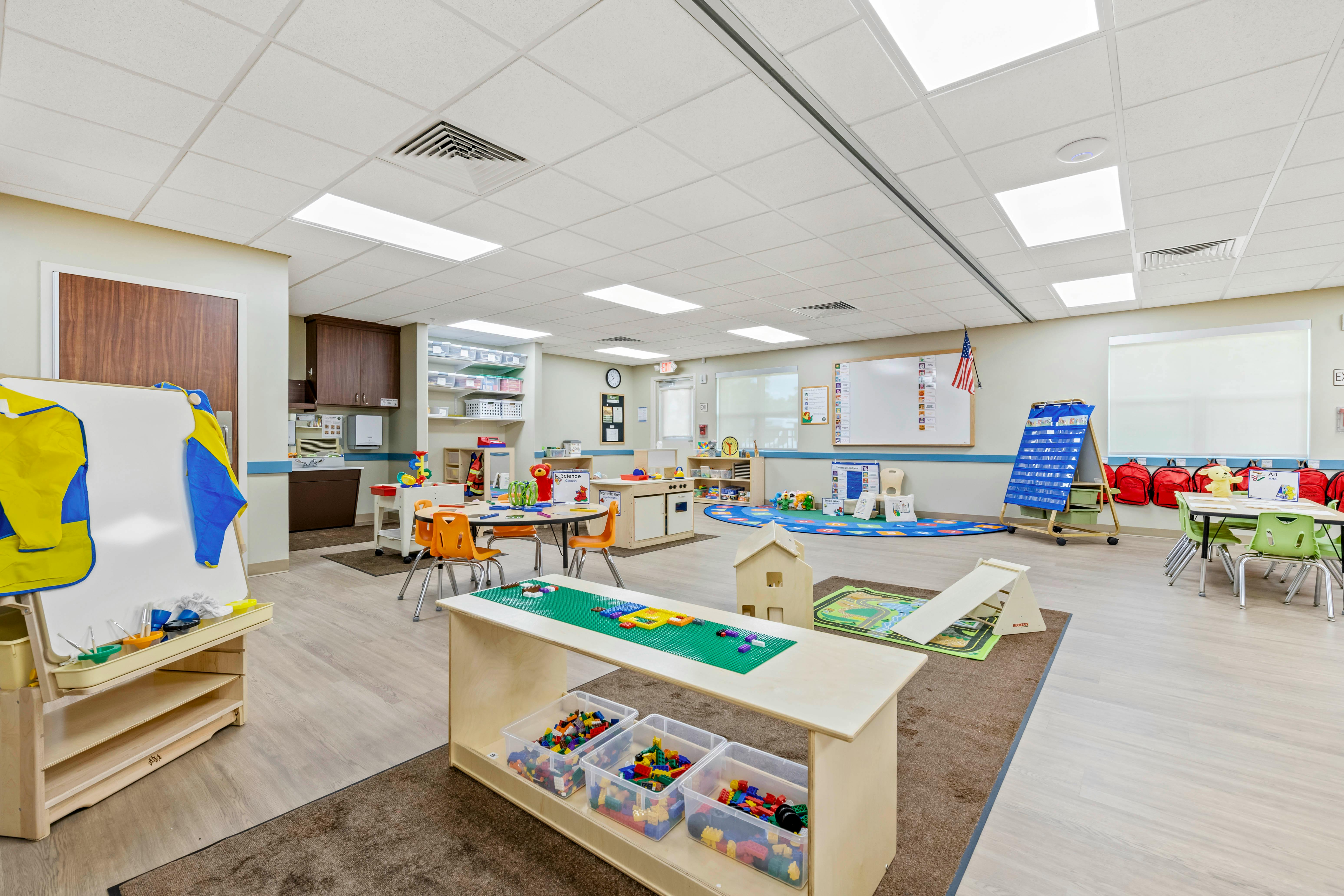 Colorful classroom with various play areas, tables, and chairs for children